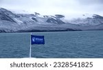 Small photo of Deception Island, Antarctica - March 4, 2022: Pennant flag on the bow of an expedition cruise ship, with snow covered mountains around the edge of the caldera by at Deception Island in the distance