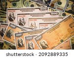 Series HH and Series EE United States Treasury Savings Bonds surrounded by US currency.  Issued by the US Government and  purchased from the U.S. Department of the Treasury.