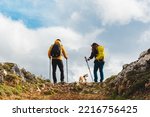 Small photo of couple of mountaineers with a backpack on a mountain route with their dog. hiker ascending a mountain peak. healthy lifestyle