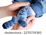 A mother woman wears blue socks to a foot baby boy, isolated on a white background. Mom dresses a leg child in clothes. Kid nine months old