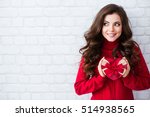 Smiling woman hold red gift box. Wall background. Concept of the New Year, Christmas and Valentine's Day.