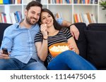Young couple watching tv at home and having fun