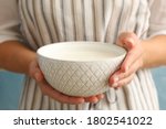 Woman in apron hold bowl of sour cream yogurt against blue background