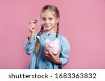 Little girl saving money in a piggybank on pink background