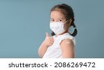 Small photo of Coronavirus Vaccination Advertisement. Happy Vaccinated Little asian girl Showing Arm With Plaster Bandage After Covid-19 Vaccine Injection Posing Over Blue Background, Smiling To Camera. New normal.