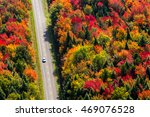 Aerial view of a car driving on a country road through a colorful forest at fall. Quebec, Canada.