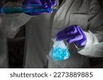 Small photo of A woman scientist performing Organic reaction under fuming condition in a laboratory. Fume, radioactive, fluorescence. A copy space black background. Organic medicinal chemistry laboratory.