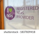 Small photo of Geelong, Victoria - May 16 2020 "I love NDIS" and "Registered NDIS Provider" logos on the door of a business. The business is Encompass Community Services and is at 93 Garden Street