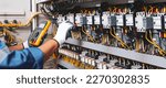 Small photo of Electricity or electrical maintenance service, Electrician hand holding measuring meter checking electric current voltage circuit breaker cable wiring check main power load center distribution board.