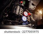Small photo of Car care maintenance and service, Hand technician auto mechanic using measuring manifold gauge check refrigerant and filling car air conditioner to fix repairing heat conditioning system.