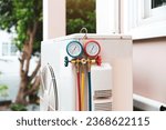 Small photo of Close up manifold gauge measuring tool on fan for check pump filling home air conditioner and checking maintenance heat fix repair and clean outdoor air compressor unit.