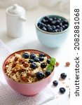 Small photo of Herculean porridge with hazelnuts, granola and blueberries in a pink plate o white table.