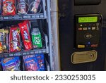 Small photo of Oakland, CA, USA July 11, 2023 Skittles candy in a vending machine. Showing where you put the money and card in as well as the candy behind the glass. Also a tap screen for your a credit card.