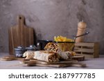 Small photo of Shawarma sandwich gyro fresh roll of lavash (pita bread) chicken beef shawarma Traditional Middle Eastern snack. On wooden background