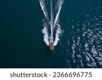 Luxury wooden big speedboat fast moving on dark water top view. Expensive wooden big boat with people moving on the water aerial view. Boat movement on the water. Motor boat in motion.