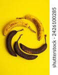 Small photo of Rotten bananas on a yellow background from above. Bananas that are beginning to spoil and bananas that have already spoiled. Yellow and brown spoiled bananas. Food waste.