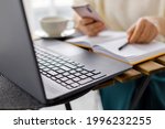 business woman works at laptop, holds smartphone in her hand and makes entries in diary. Business planning and tasks for day or week. Female in business. Keyboard laptop