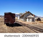 Small photo of Historic Rsilroad Depot Near the Mountains with an Old Wooden Boxcar in the Train Yard