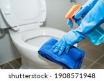 Small photo of close up hands women wearing protect glove blue using liquid cleaning solution cleaning flush toilet, disinfection and hygiene concept