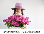 girl in a hat and a bouquet of roses in her hands