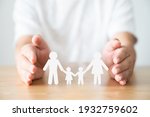 Hand protecting family on wood table. Healthcare and life insurance concept