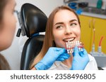 Small photo of Dentist selects a shade of teeth whitening using shade guide to young patient with perfect smile.