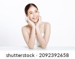 Small photo of Asian woman with a beautiful face gathered in a brown ponytail and clean fresh smooth skin. Cute female model with natural makeup and sparkling eyes on white isolated background.