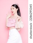Small photo of Cute Asian woman model gathered in ponytail with korean makeup style on face have plump lips and clean fresh skin wearing pink camisole holding handbag on isolated pink background.