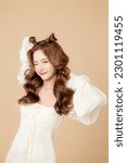 Small photo of Young Asian beauty woman curly long hair with korean makeup style on cute face and perfect skin on isolated beige background. Facial treatment, Cosmetology, plastic surgery.