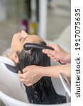 Small photo of Hair rinsing. Hair stylist rinsing hair to her customer in a hair salon