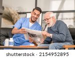 Small photo of Old man and his caretaker laughing at a news item