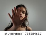 Small photo of Palm. Pretty humourless dark-haired young woman staring and having long hair and closing her face with her palm