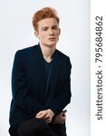 Small photo of Cupcake. Handsome humourless red-haired young man wearing a black jacket and staring and having a modern haircut