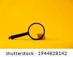 View of the coins through a magnifying glass. Increase in money, financial growth. On a yellow background. A small amount of money turns into a lot of money. The concept of  rising prices, rising rate