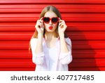 Pretty woman in red sunglasses blowing lips kiss over colorful background