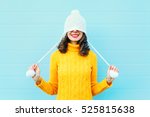 Fashion happy young woman in knitted hat and sweater having fun over colorful blue background