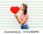 pretty woman making air kiss with red balloons heart shape over white background