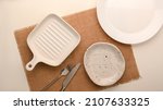 Small photo of Empty white ceramic plate on a white background with a knife and fork on placemat. Minimalist plates design. top view, flat lay