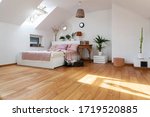 White interior of bedroom with wooden floor and double bed with pink pillows. Bright cozy bedroom in scandinavian style in the attic.