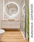 Small photo of Luxury bathroom with glass to shower, round mirror with led lights, stylish washbasin and wooden floor. Modern interior of bathroom with wc and bath. Vertical.