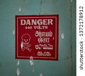 Small photo of Indian (Tamil) Electrical Safety sign - Danger - weathered, found on old motor control switchboard, with skull and crossbones.