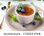 Creme brulee dessert with blueberries and mint leaves. Close up.
