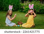 Small photo of A two girls during Easter egg hunt and putting Easter eggs in baskets