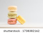 Small photo of A vertical stack of three macarons against a bright white background with an additional yellow macaron leaning inwards.