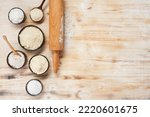 Bowls with different types of flour, wooden spoons and rolling pin on a white and brown wooden table, top view. Space for text.