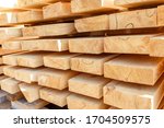 Stack of new wooden studs at the lumber yard. Timber on the construction site to dry. Background of sawed and processed wood of coniferous breeds