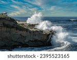 WAVES CRASHING ON THE ROCKY SHORELINE IN LA JOLLA CALIFORNIA NEAR THE LIFEGUARD STATION AND THE CHILDRENS POOL WITH A NICE LIGHTLY CLOUDY SKY