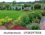 Blooming garden. A flower bed with bright shrubs and trees. Backyard lawn.