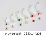 Oropharyngeal airway cannula in a white surface aligned by the size of each cannula. Small to big size. 0 to 5 size of a guedel cannula 