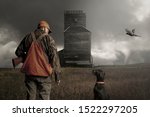 A hunter and his dog looking at each other in a field with an approaching tornado in the distance.